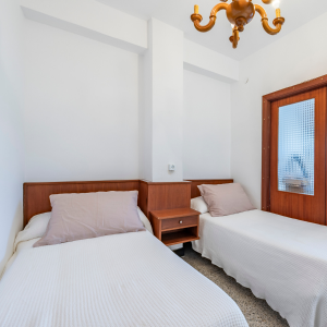 Habitación luminosa con dos camas separadas y armario de madera en piso turístico cerca de la playa