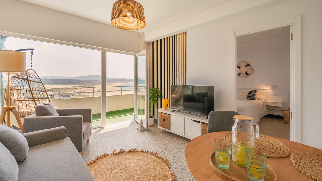 Salón con sofá y grandes ventanales en apartamento cerca de la playa en Valdoviño