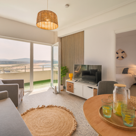 Salón con sofá y grandes ventanales en apartamento cerca de la playa en Valdoviño