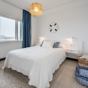 Vista de la suite principal con ropa de cama blanca y luz natural en alojamiento cerca de la playa